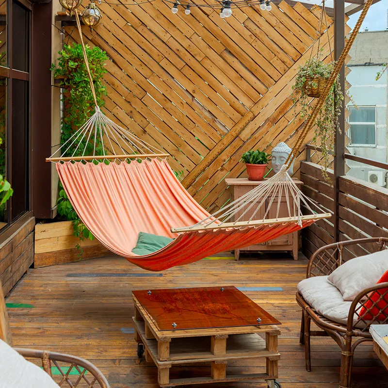 Terrasse en bois blanchie par le sel, avec un brise-vue en lattes de bois et quelques pots de plantes aux feuilles vertes