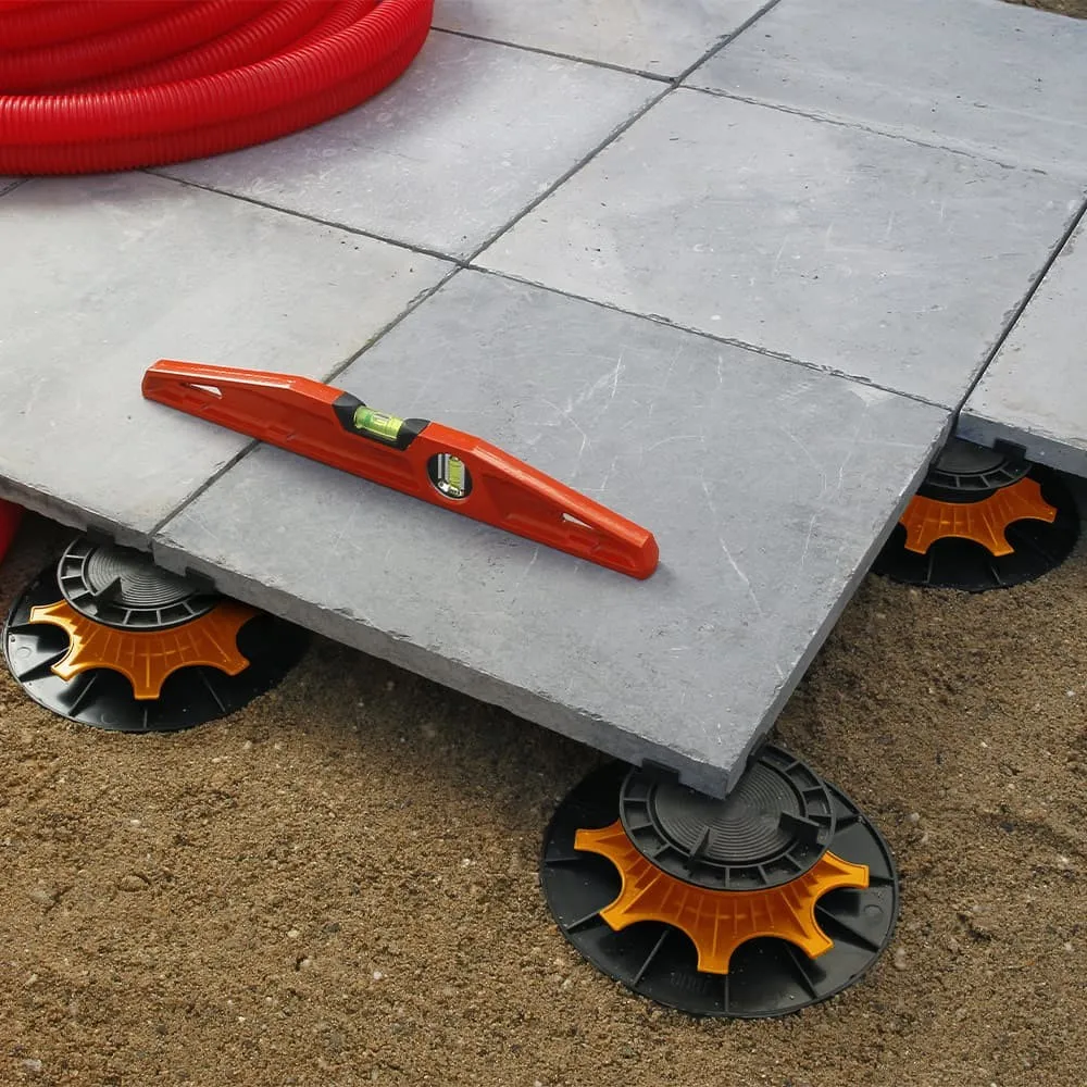 Terrasse en dalles claires posées sur plots réglables, vue de trois quarts avec un pot de lavande posé au bord et la mer à l'horizon