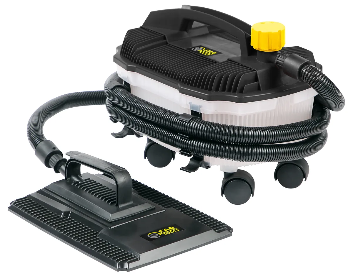 Décolleuse électrique appuyée contre un mur, tuyau flexible enroulé, sol protégé par une bâche et rouleau de papier peint enlevé à côté