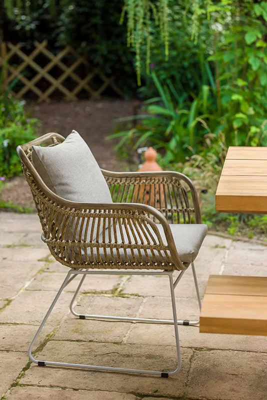 Fauteuil en corde tressée et bois blanchi sur une terrasse en pierre, vue sur la mer sous un ciel gris clair